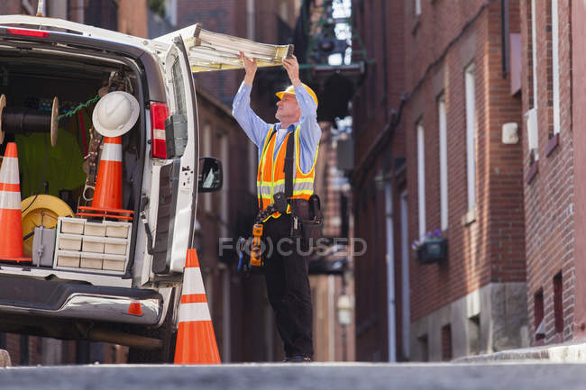Cable lineman removing ladder from his truck — Stock Photo