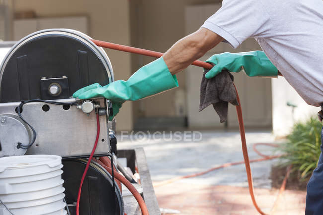 Pest control technician pulling hose from reel in service truck — Stock Photo