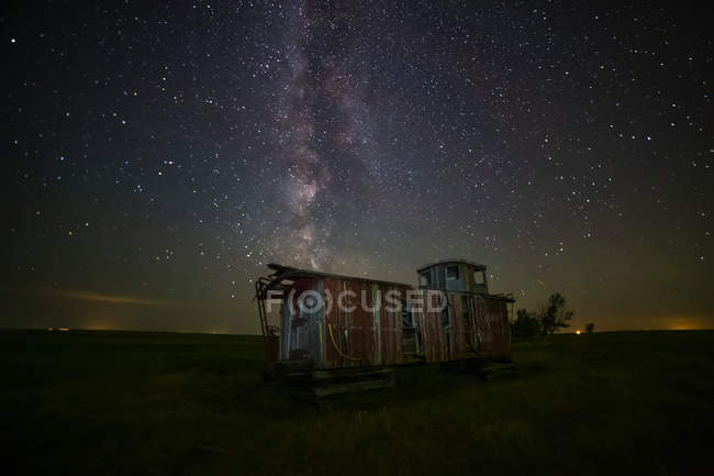 Old caboose à noite sob um céu brilhante e estrelado; Coderre, Saskatchewan, Canadá — Fotografia de Stock