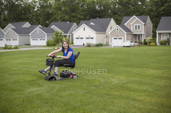 Молода жінка з Церебралом Пальсі їде на своєму скутері на газоні. — стокове фото