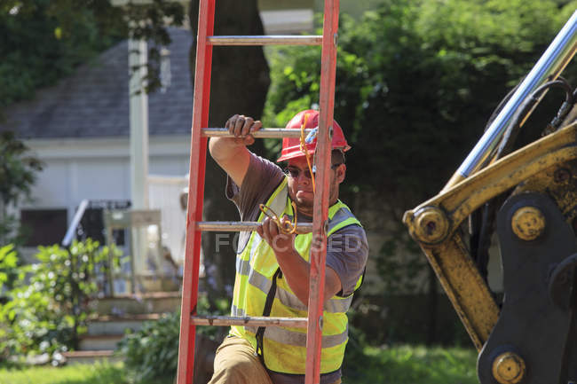 Trabajador de la construcción subiendo escalera abajo en el apuntalamiento - foto de stock
