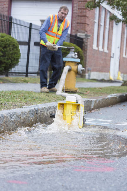 Water department technician opening fire hydrant to flush water mains — Stock Photo