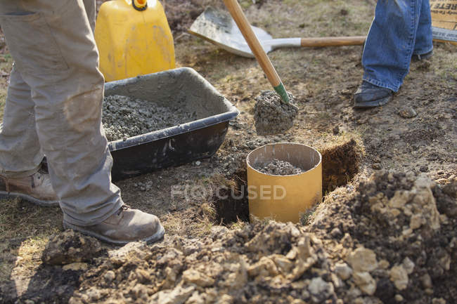 Плотник добавляет цемент в трубу опоры палубы — стоковое фото