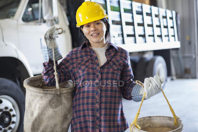Female power engineer preparing canvas buckets in service garage — Stock Photo