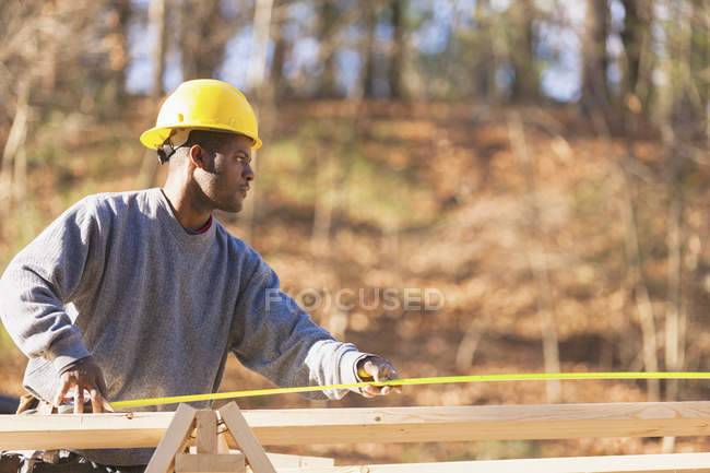 Carpenter measuring board length — Stock Photo