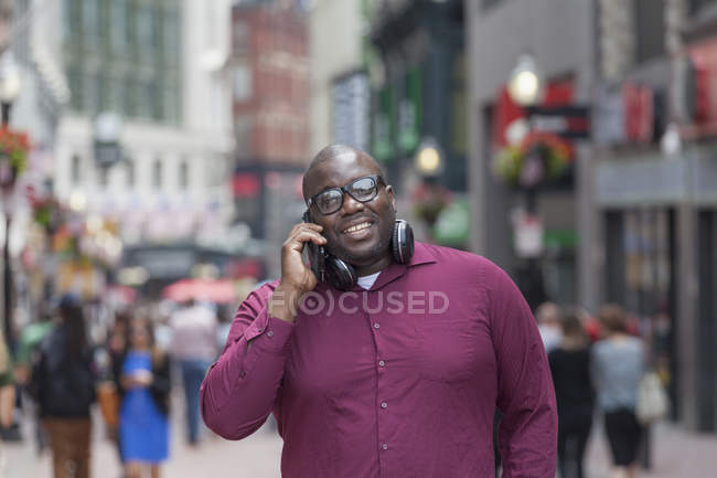 Hombre con TDAH hablando en un teléfono móvil en la calle de la ciudad - foto de stock