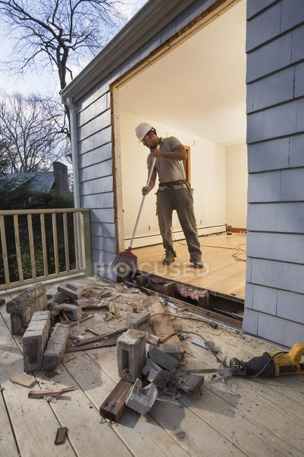 Hispanic carpenter cleaning newly cut door entrance from house to deck — Stock Photo