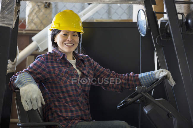 Female power engineer driving a forklift truck in service garage — Stock Photo