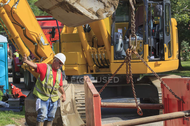 Construction foreman guiding placement of shoring into hole — Stock Photo