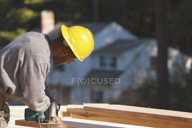 Carpenter cutting bevel on rafter with a circular saw — Stock Photo