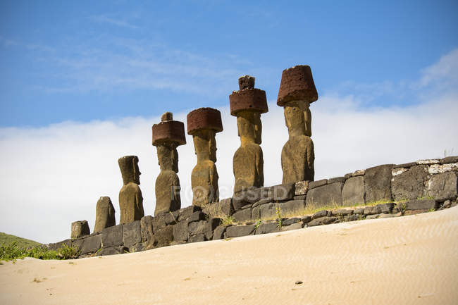 Une pente sablonneuse mène l'œil vers une plate-forme et une rangée de cinq moais vus de derrière, Île de Pâques, Chili — Photo de stock