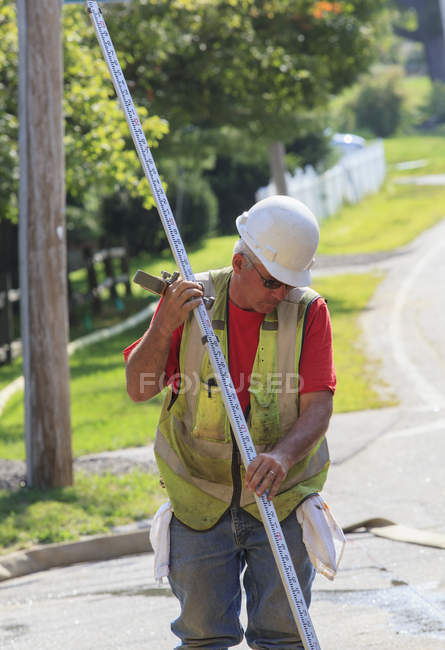 Construction supervisor using surveying rod — Stock Photo