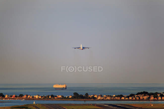 Avión despegando desde el aeropuerto Logan con Winthrop, Boston, Massachusetts, EE.UU. - foto de stock