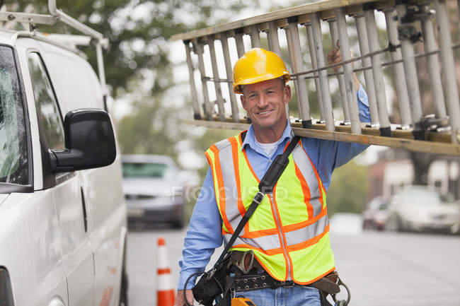 Cable lineman carrying ladder from service truck — Stock Photo