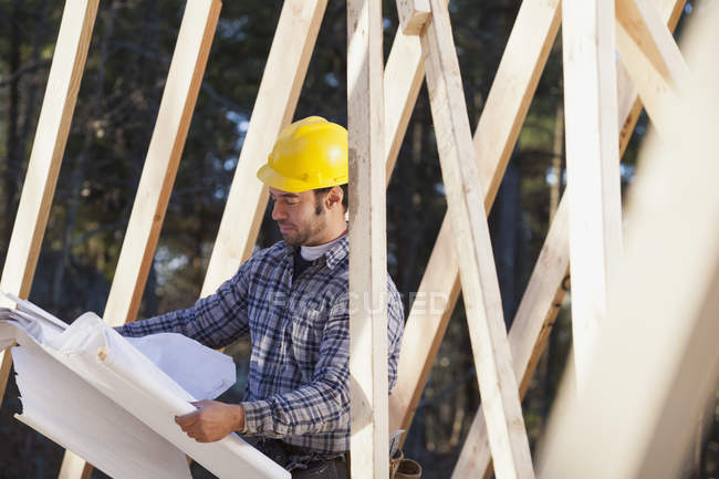 Carpenter reading house plans for house construction — Stock Photo