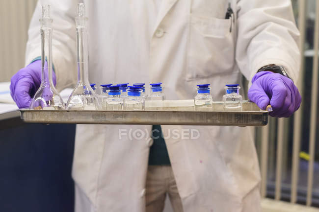 Técnico de laboratorio sosteniendo bandeja de muestras calibradas - foto de stock