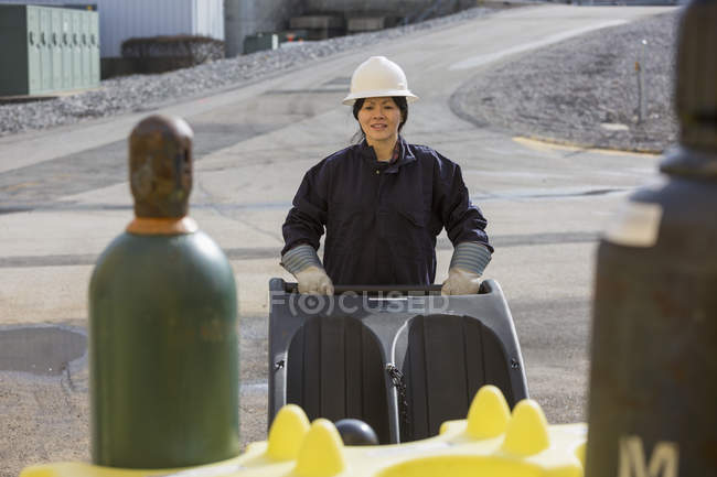 Женщина-энергетик с помощью тележки со сжатым газом на электростанции — стоковое фото