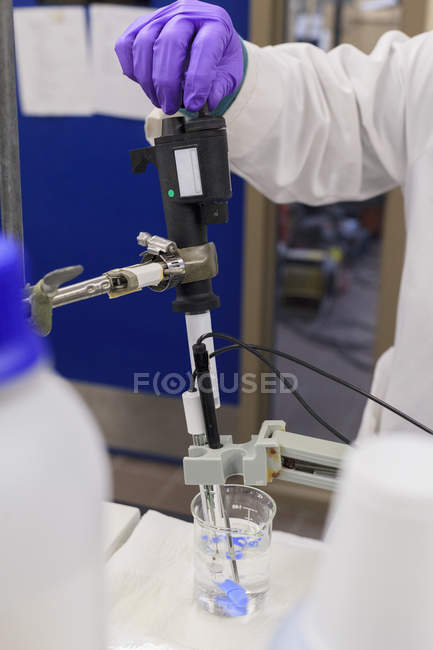 Tecnico di laboratorio che aggiunge reagente al campione durante la misurazione del pH — Foto stock