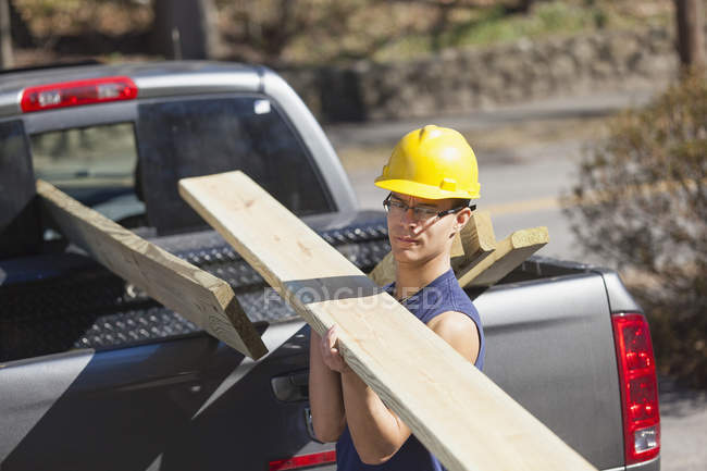 Falegname ispanico che porta legno trattato a pressione da camion a cantiere — Foto stock