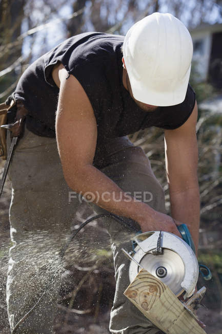 Carpintero hispano cortando vigas de cubierta con una sierra circular - foto de stock