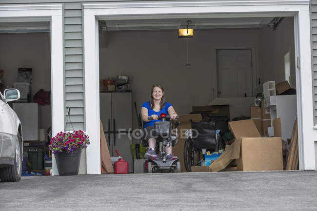 Jeune femme avec paralysie cérébrale entrer dans son scooter dans le garage — Photo de stock