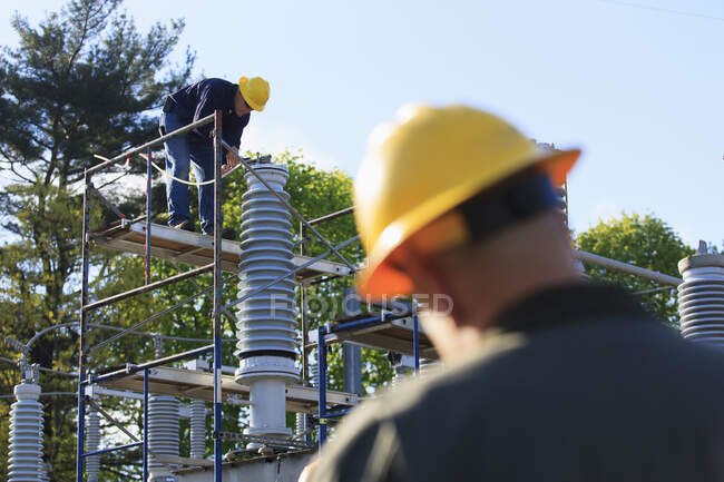 Power engineer performing maintenance on fluid filled high voltage insulator — Stock Photo