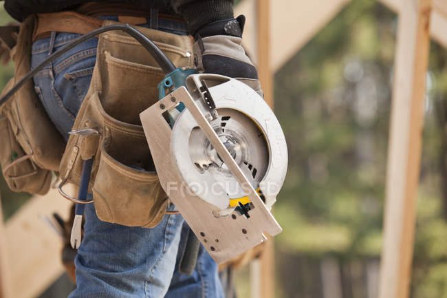 Carpenter carrying a circular saw, cropped image — Stock Photo