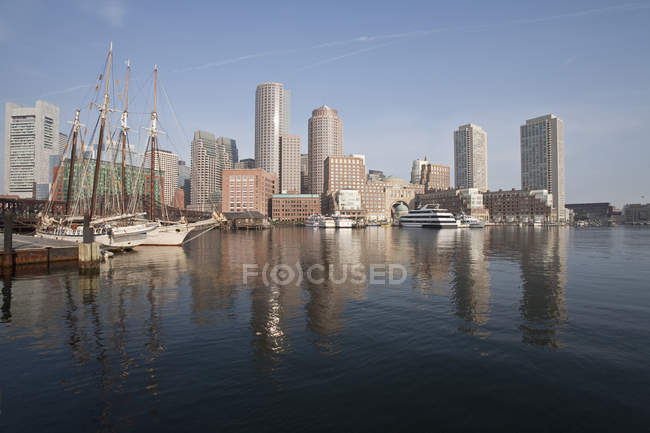 Barcos con distrito financiero en un puerto, Rowes Wharf, Boston Harbor, Boston, Massachusetts, EE.UU. - foto de stock