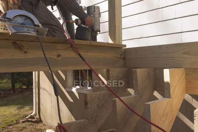 Carpenter nailing decking at stair stringers — Stock Photo