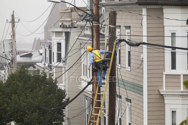 Cable lineman assessing cable distribution wiring on poles in the city — Stock Photo