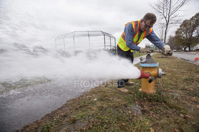 Water department technician opening fire hydrant to flush water pipes — Stock Photo