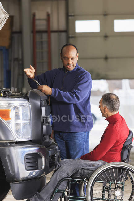Automotive tecnico di manutenzione e supervisore con lesioni del midollo spinale discutendo riparazione — Foto stock