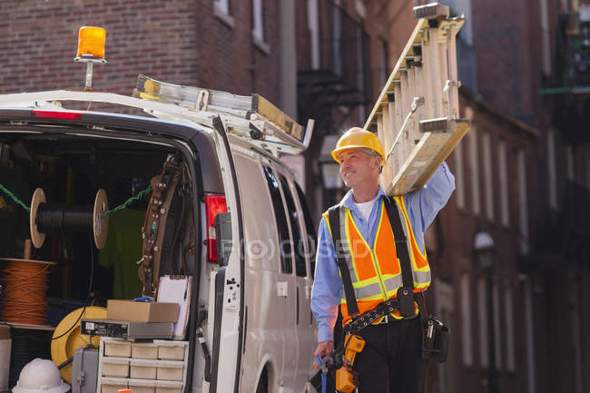 Cable installer preparing to climb the line with ladder — Stock Photo