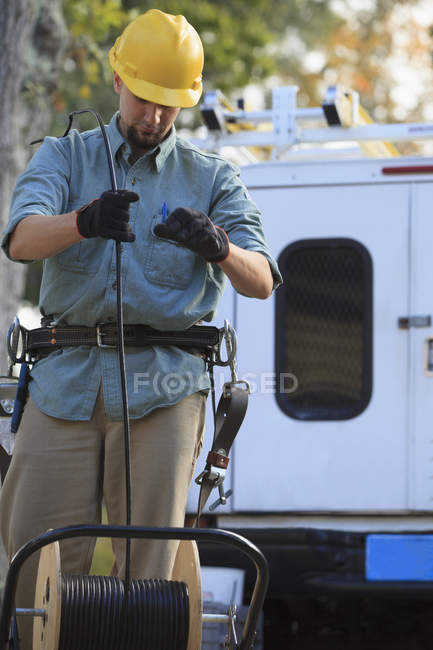 Cable lineman pulling cable from reel at site — Stock Photo