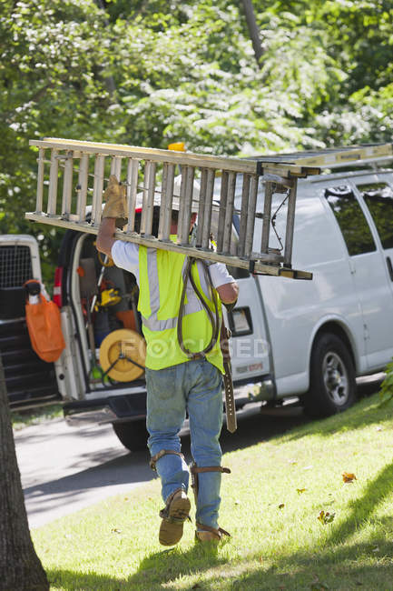 Lineman portant une échelle de retour à son camion — Photo de stock