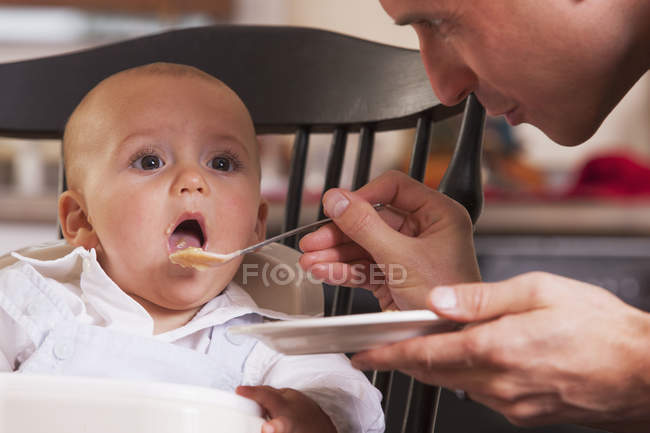 Отец кормит своего сына ложкой — стоковое фото