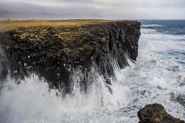 Wellen schwappen gegen die Klippen entlang der Küste; Arnarstapi, Schlangenschnäpse, Island — Stockfoto