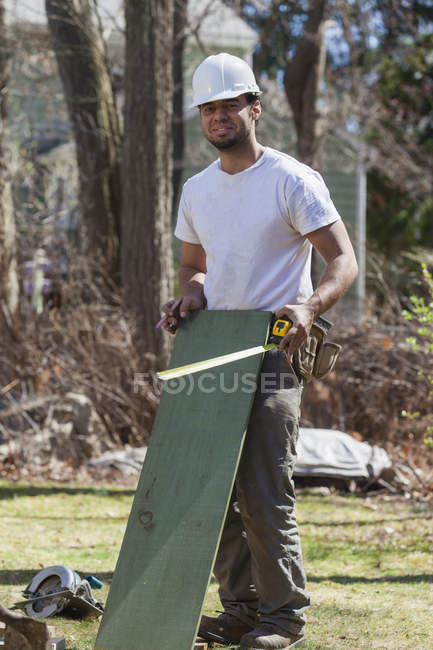 Hispanic carpenter with pressure treated wood for concrete form — Stock Photo