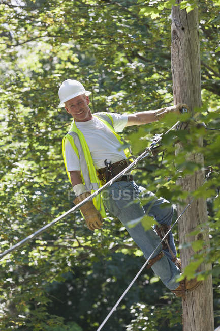 Lineman on a pole working on phone and cable wires — Stock Photo