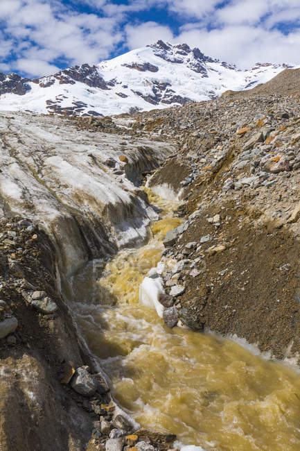 Um fluxo de água derretida desce Castner Glacier com Mount Silvertip subindo ao fundo; Alaska, Estados Unidos da América — Fotografia de Stock