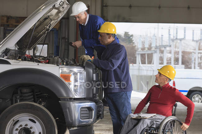 Power plant engineers one with spinal cord injury reviewing utility truck maintenance — Stock Photo