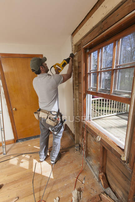 Falegname ispanico con sega alternata per rimuovere la finestra e tagliare la porta di accesso — Foto stock