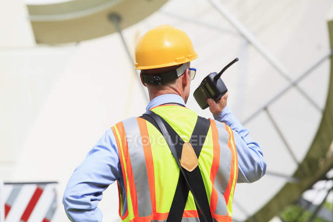Communications engineer using walkie-talkie at satellite antenna facility — Stock Photo