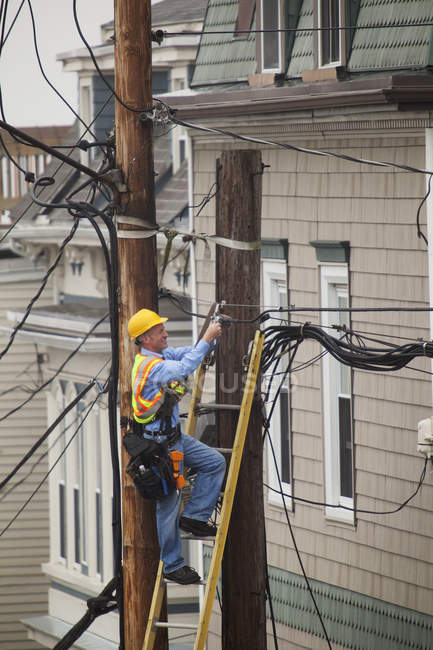 Câble lineman installant un filtre sur les poteaux électriques de la ville — Photo de stock