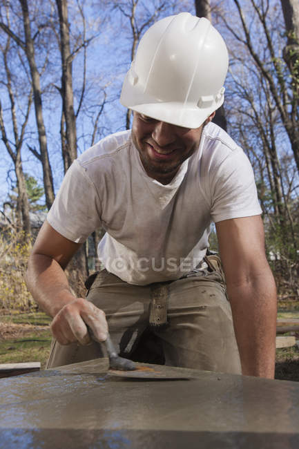 Латиноамериканский плотник, использующий лопатку, чтобы сгладить бетон для лестничной опоры — стоковое фото