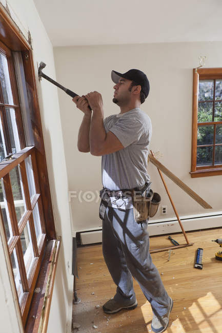 Falegname ispanico rimozione cornice finestra dalla stanza in casa — Foto stock
