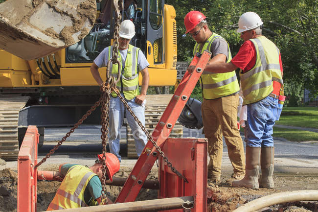 Trabalhadores da construção civil se preparando para descer buraco com escada — Fotografia de Stock