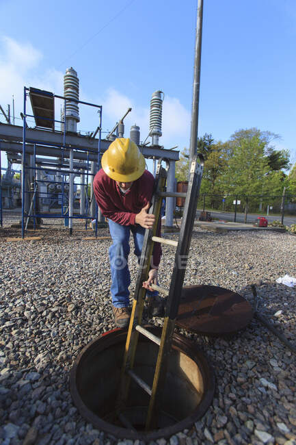 Energietechniker platziert Leiter in Schacht an Hochspannungsverteilerstation — Stockfoto