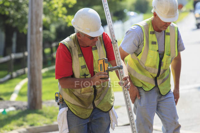 Construction supervisor using electronic surveying rod — Stock Photo