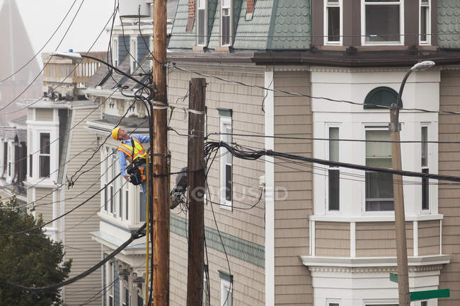 Cable lineman climbing up a ladder on city power pole — Stock Photo